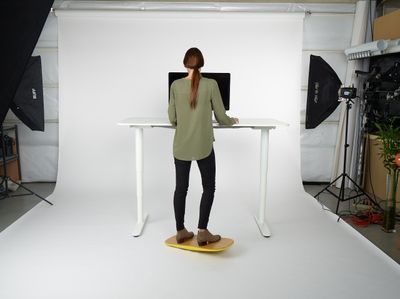 a woman standing at a desk in front of a camera