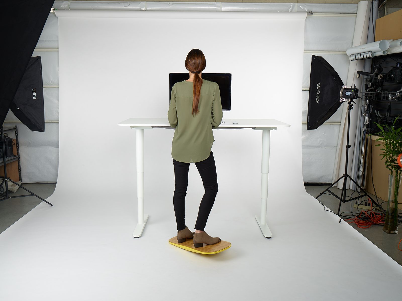 a woman standing in front of a desk with a laptop on it