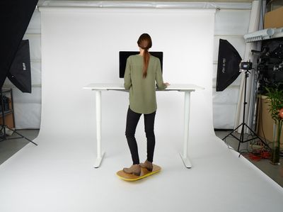 a woman standing at a desk in front of a camera