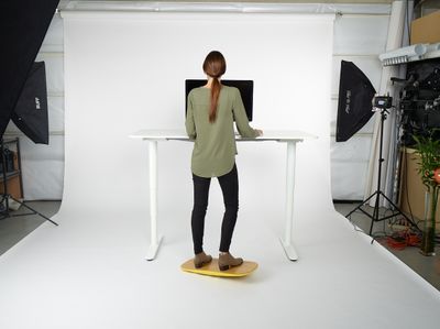 a woman standing at a desk in front of a camera