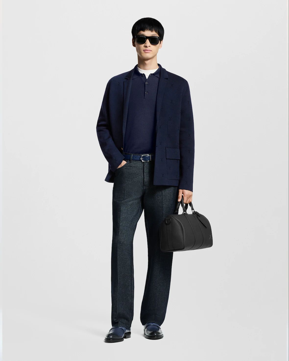 a man in a suit and sunglasses holding a bag