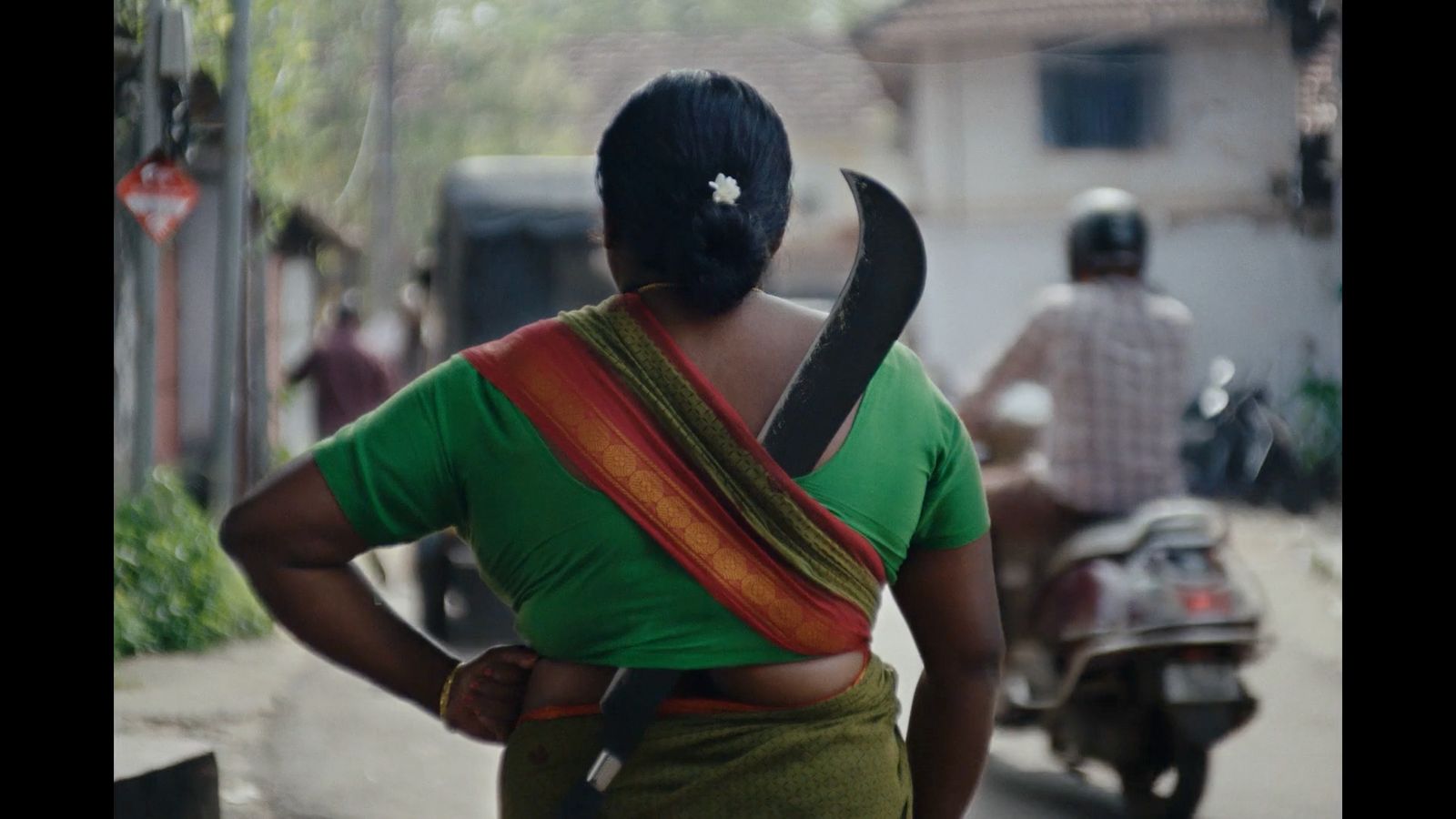 a woman in a green shirt is carrying a large object on her back