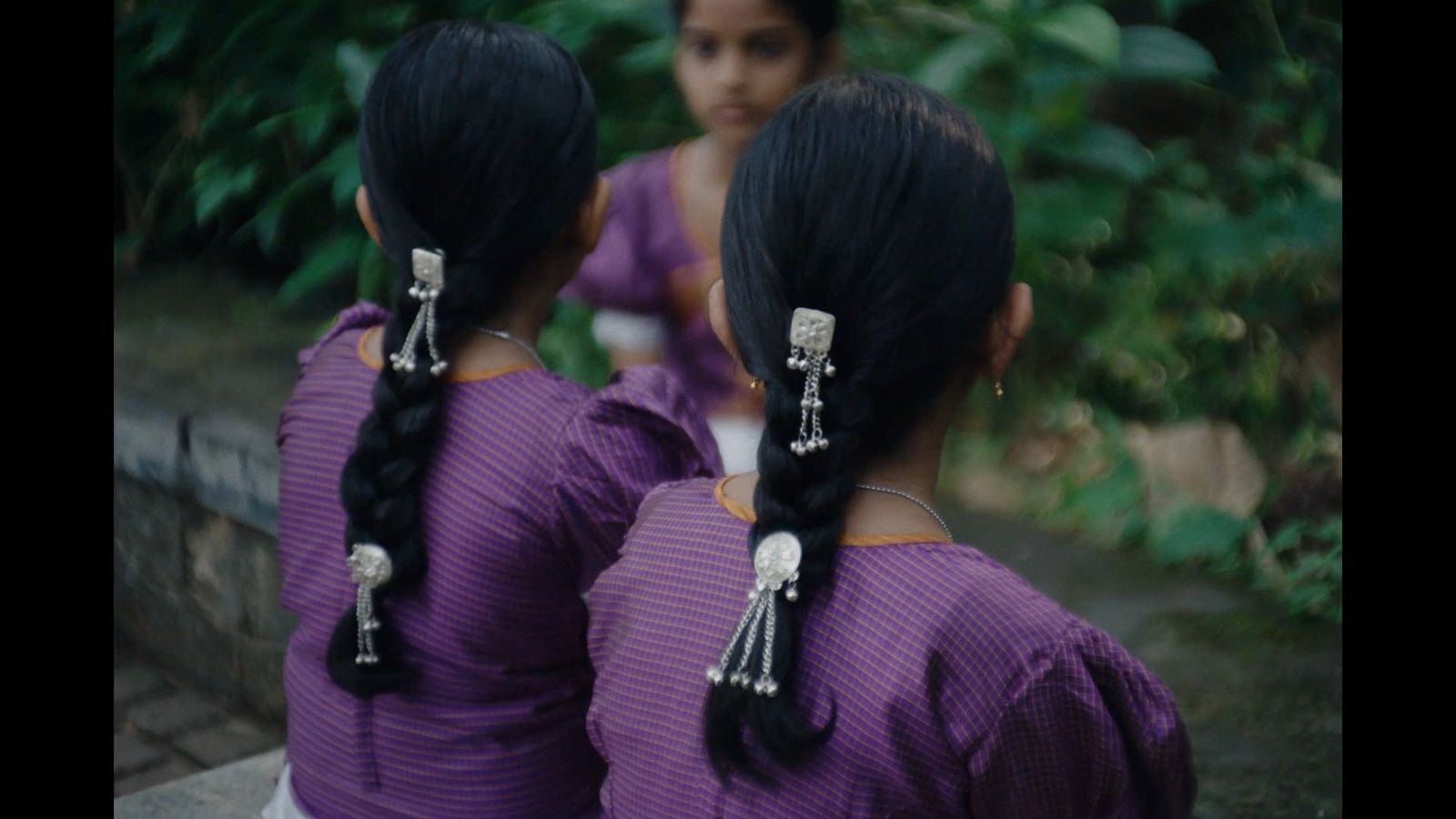 two young girls with long black hair are looking at each other