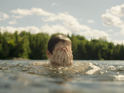 a person swimming in a body of water with trees in the background