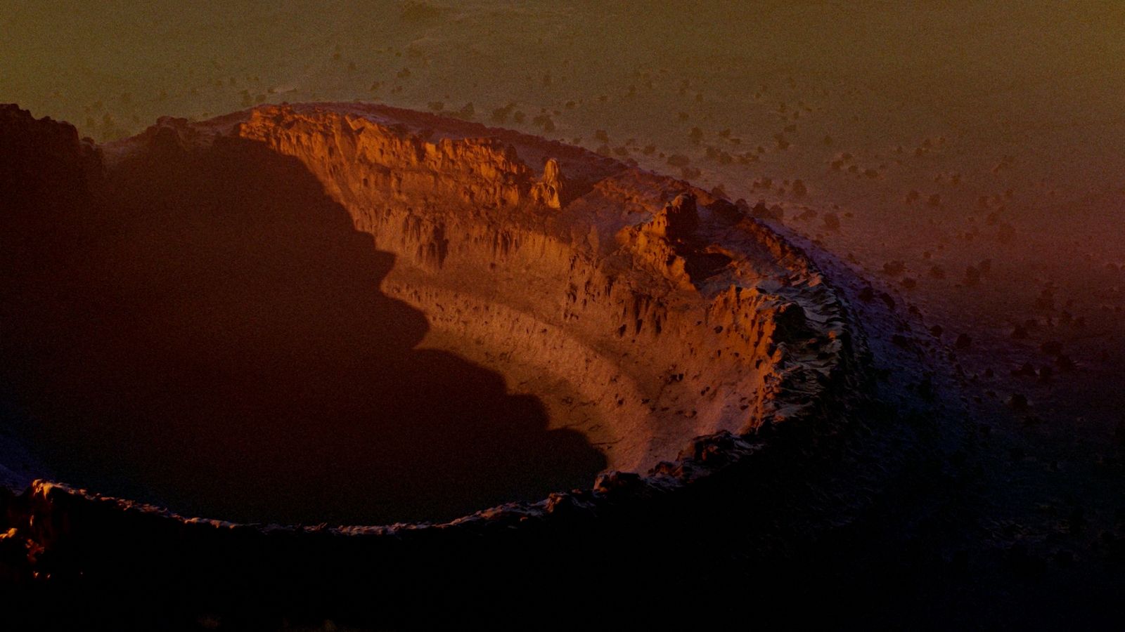 a view of a large crater in the middle of a desert