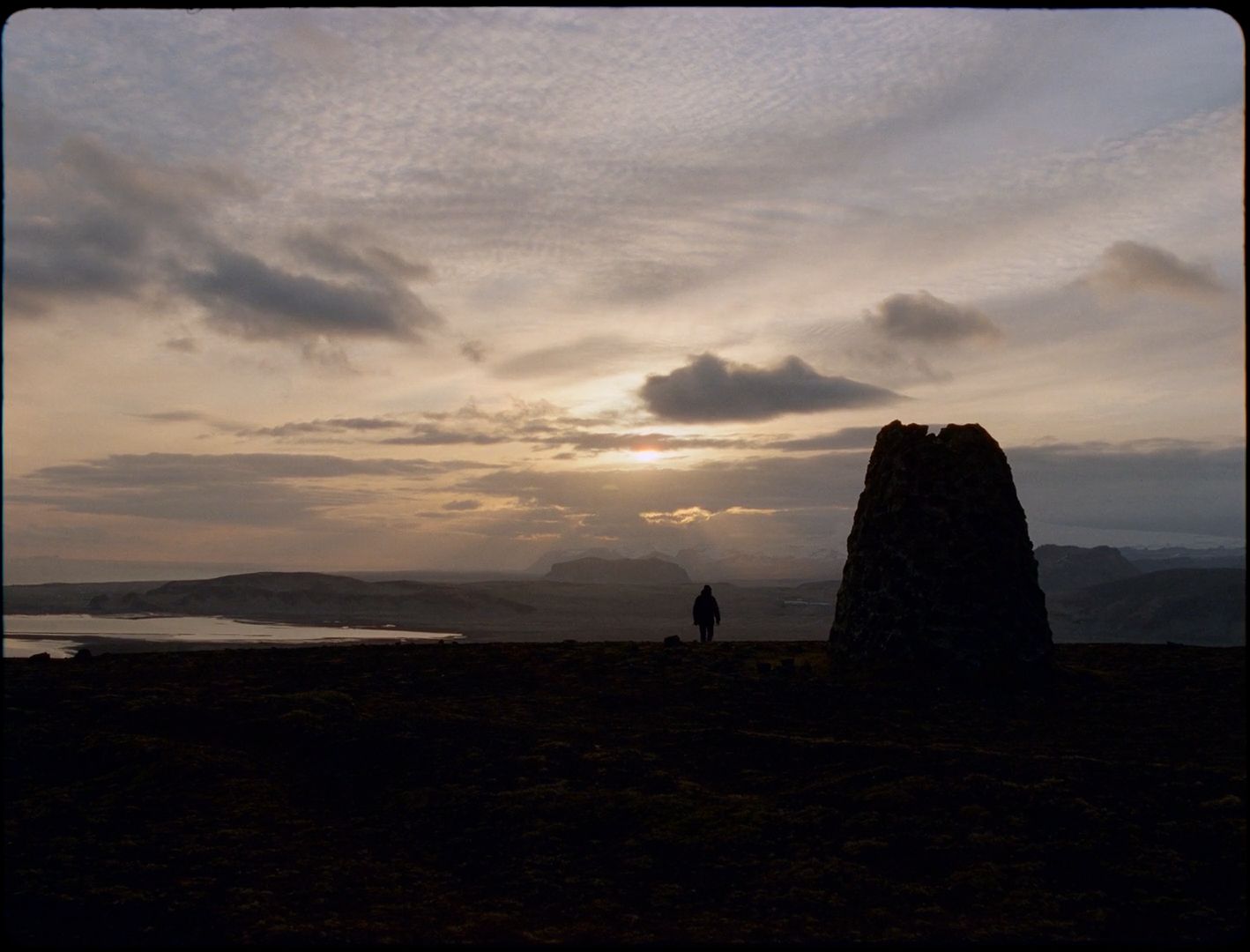 a person standing on top of a hill near a body of water