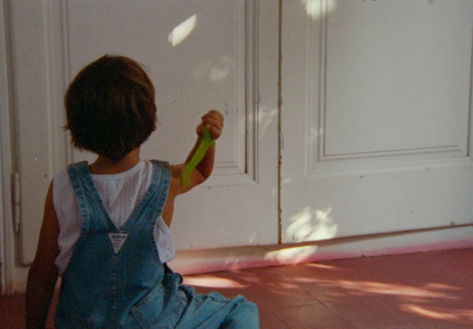 a little girl sitting on the floor holding a green umbrella