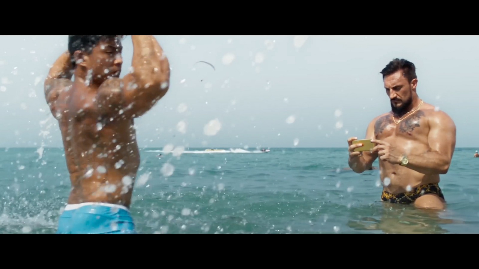 a man standing in the ocean next to another man