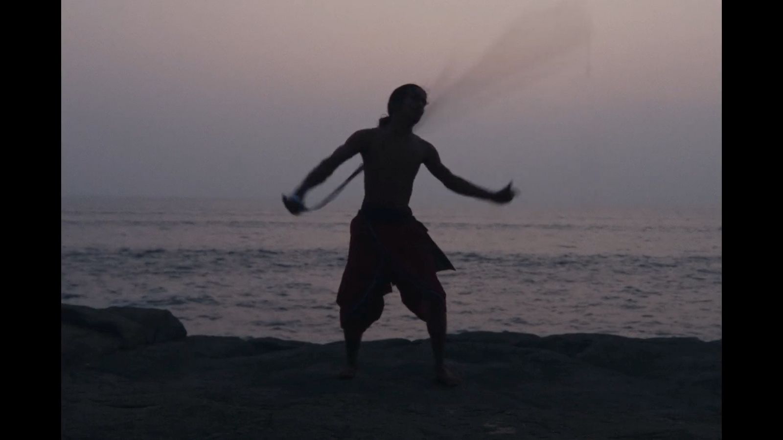 a man standing on top of a beach holding a racquet