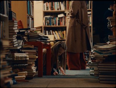 a young girl sitting on the floor in front of a pile of books