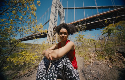 a woman sitting on a rock in front of a bridge