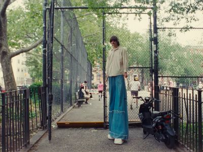 a woman standing in front of a fence with a scooter