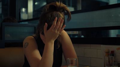 a woman sitting at a table with her hands covering her face