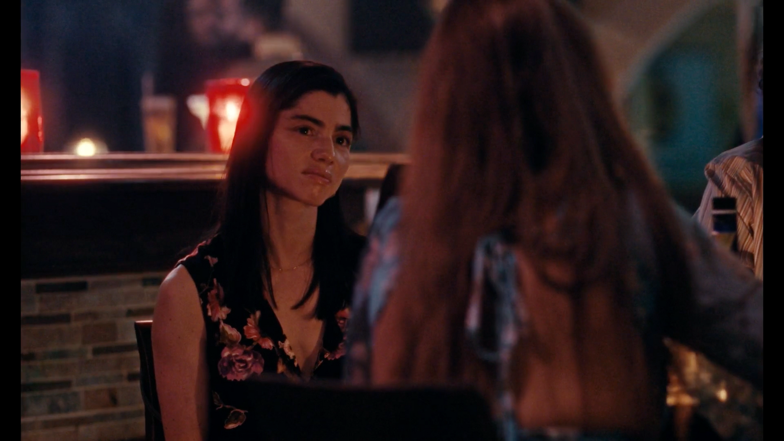 a woman sitting at a table talking to another woman