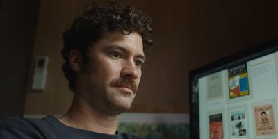 a man with curly hair looking at a computer screen