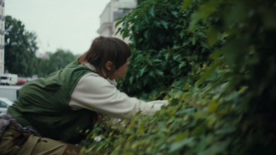 a woman is picking leaves off of a bush