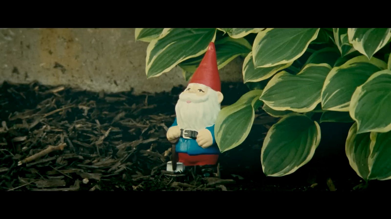 a small gnome figurine sitting in front of a plant