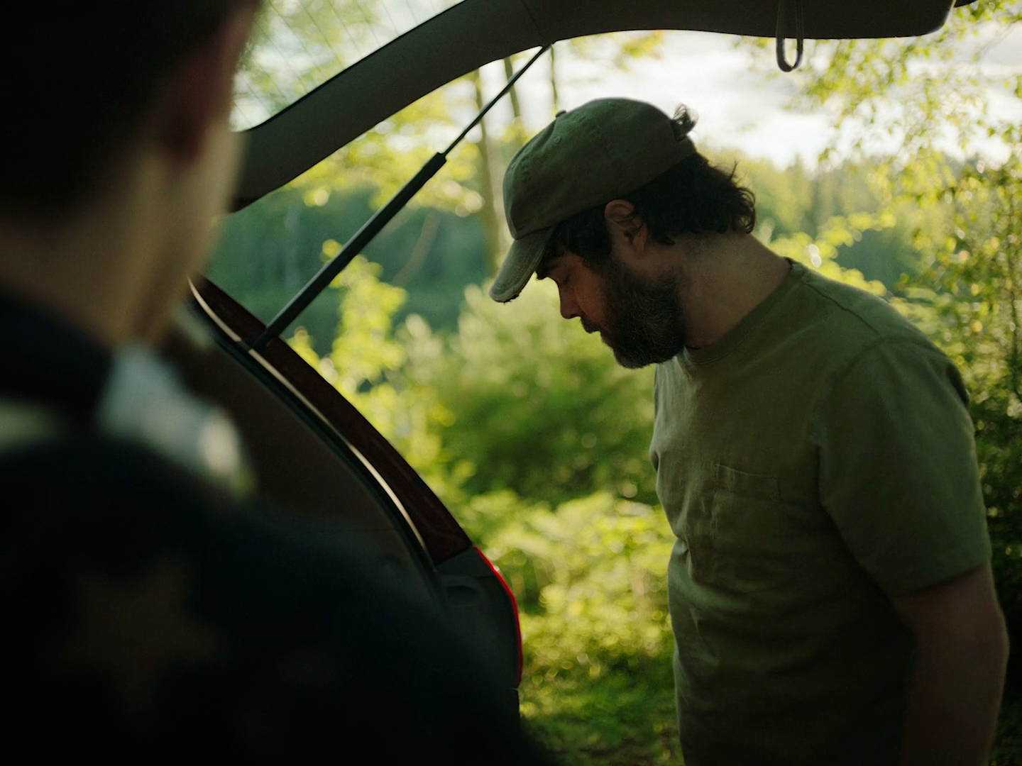 a man standing next to a car in a forest