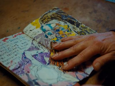 a person's hand on a book with writing on it