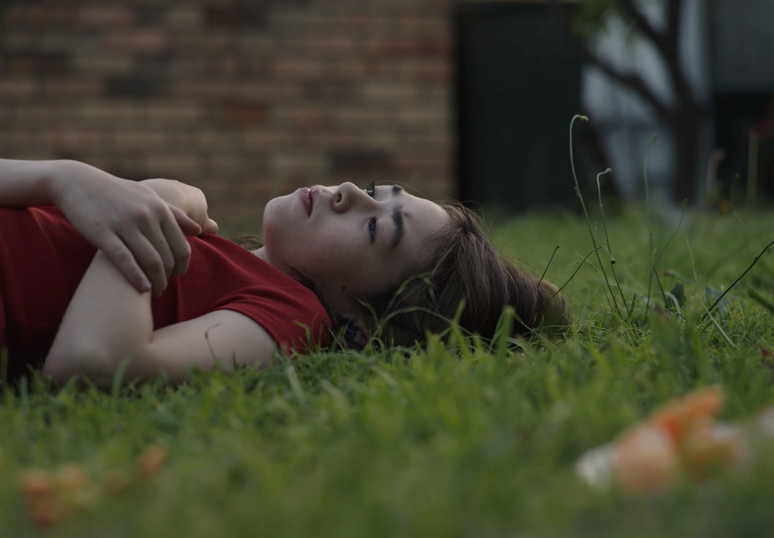 a woman laying in the grass with her eyes closed