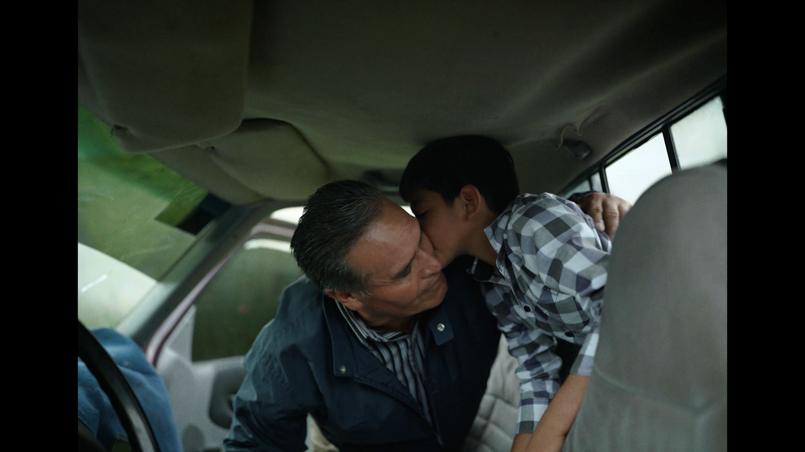 a man and a woman kissing in the back of a car