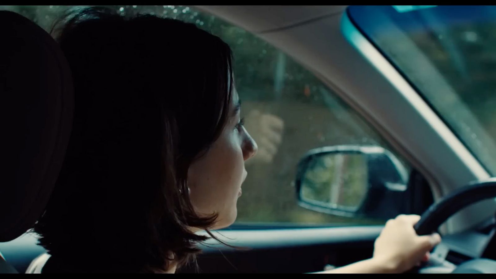 a woman driving a car with a steering wheel