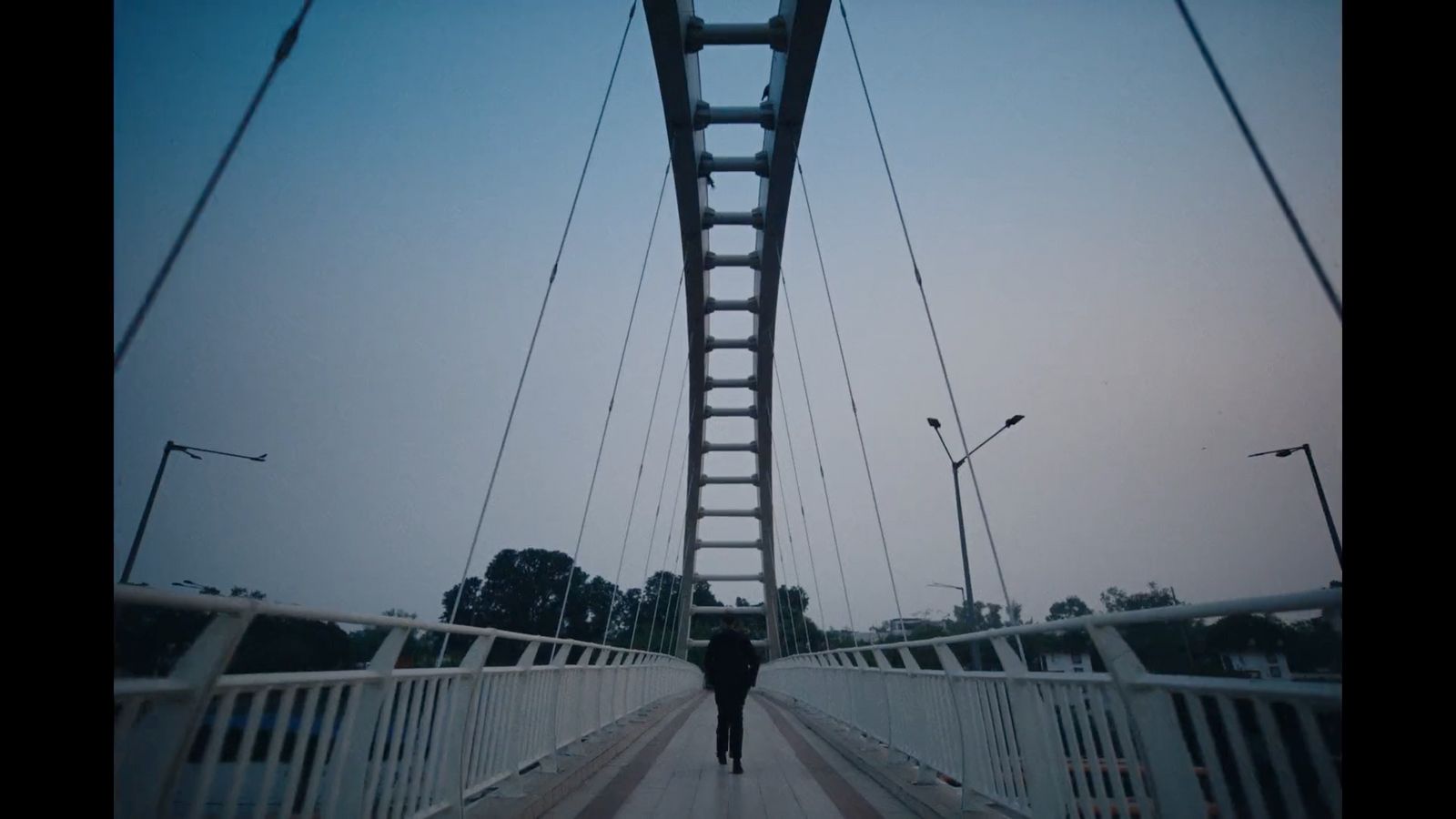 a person walking across a bridge with a sky background