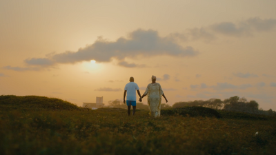 a couple of people walking across a lush green field