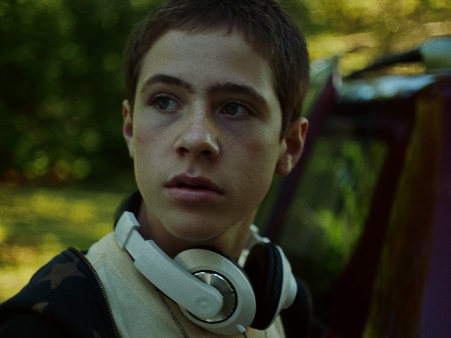 a young man with headphones standing in front of a car