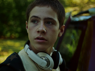 a young man with headphones standing in front of a car