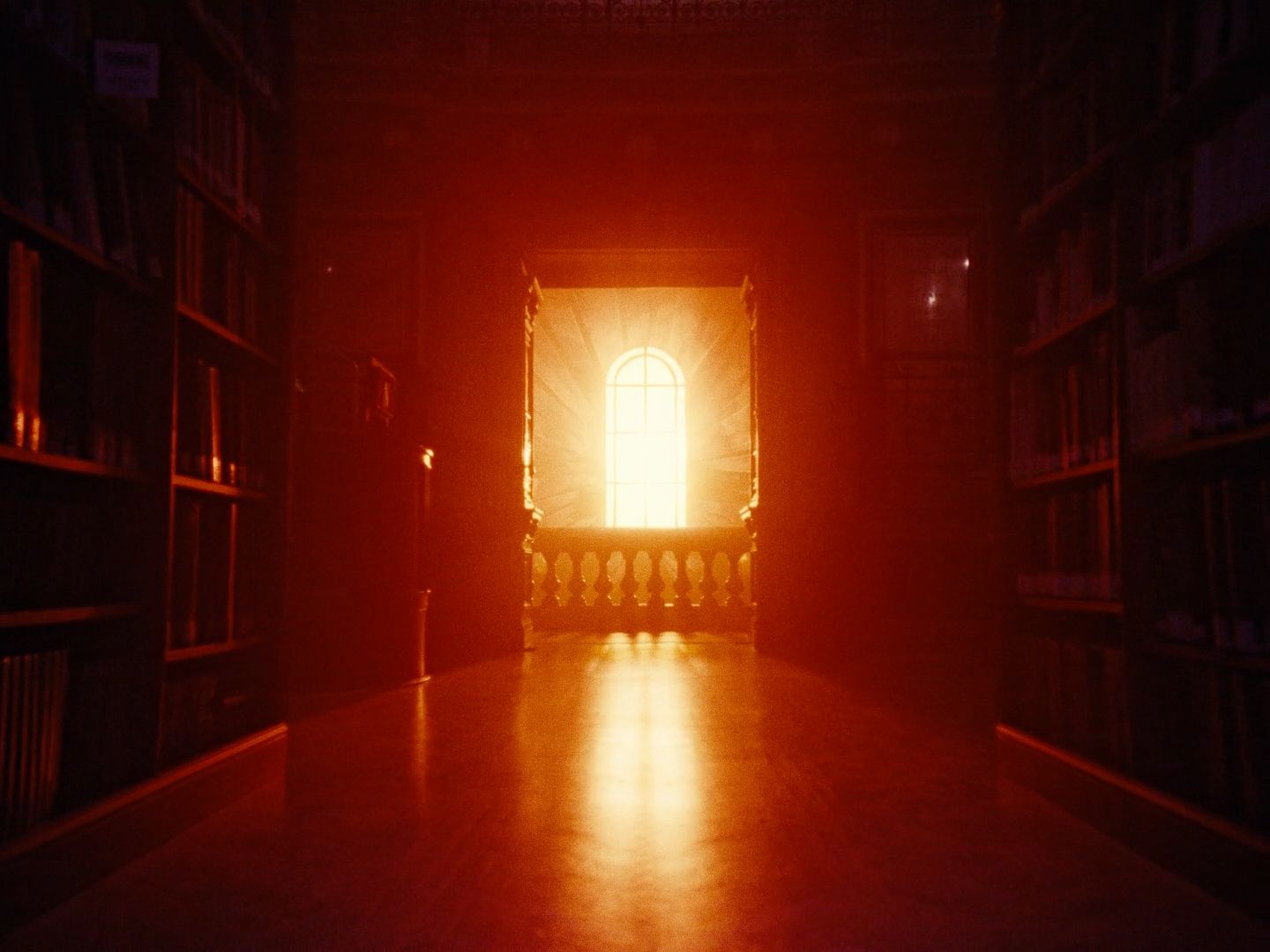 a dimly lit room with bookshelves and a window