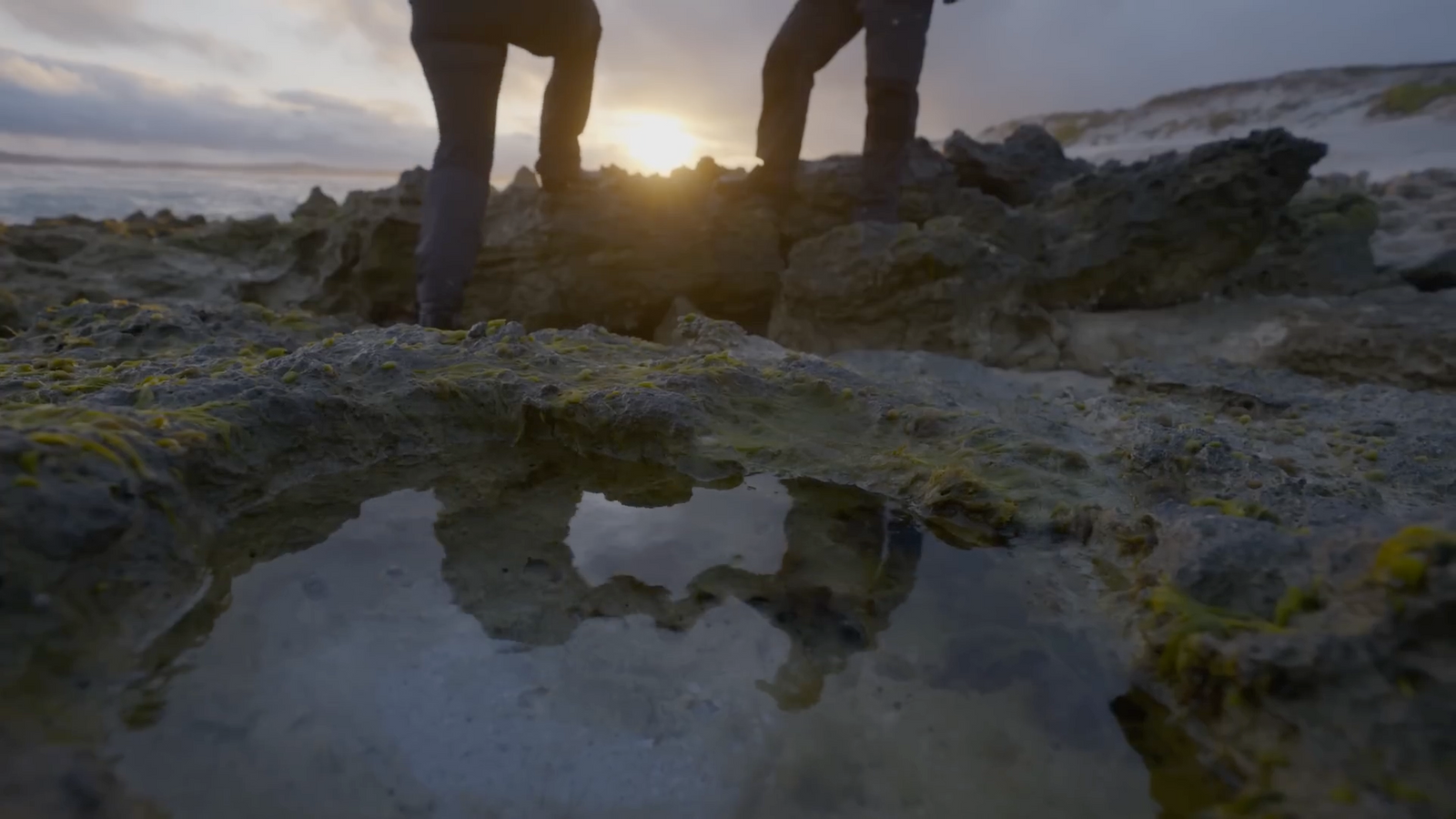 a couple of people standing on top of a rocky hillside