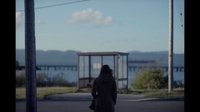 a woman walking down a street next to a bus stop