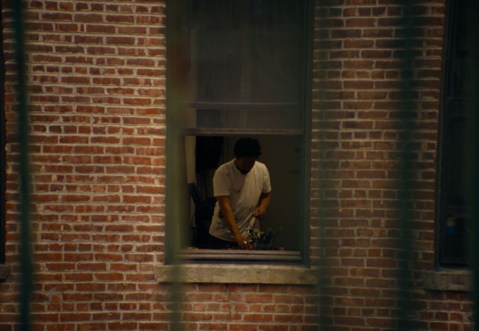 a man in a white shirt is looking out of a window