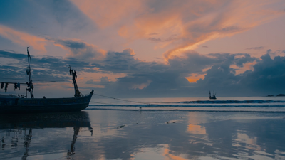 a boat sitting on top of a beach under a cloudy sky