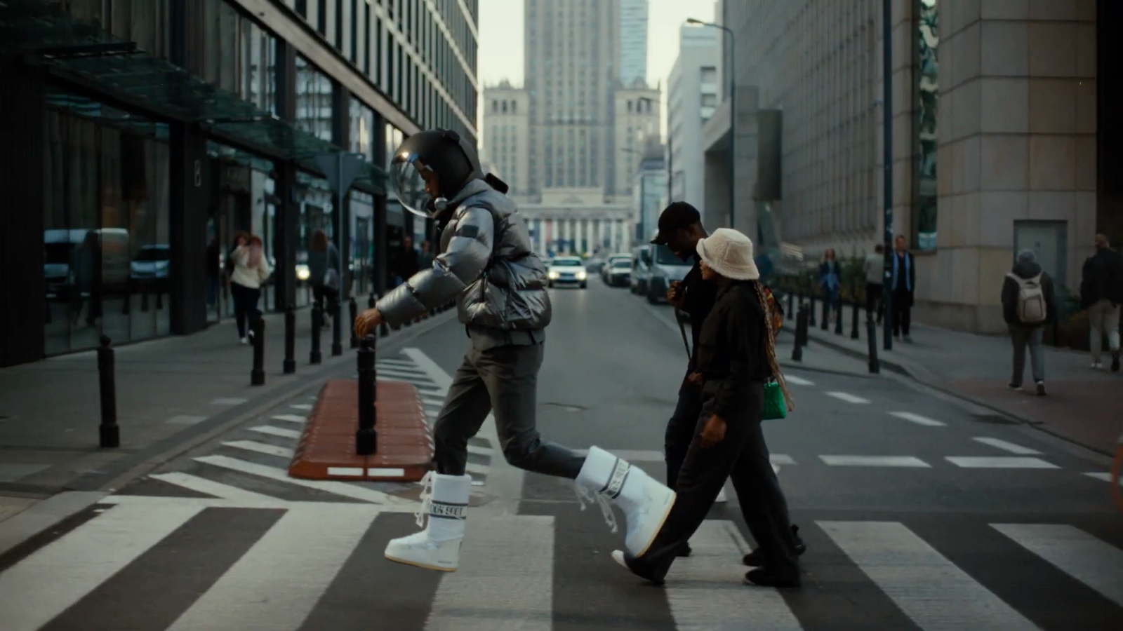 a man walking across a cross walk in a city