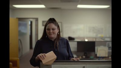 a woman standing at a counter holding a piece of paper