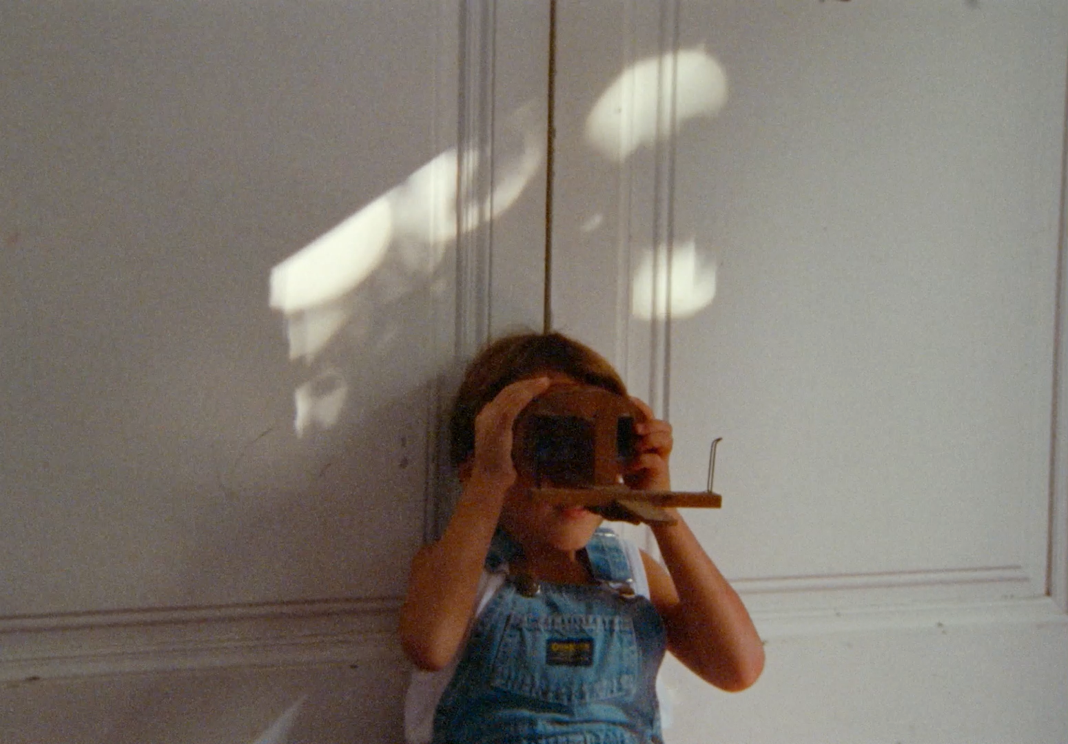 a little girl taking a picture of herself with a camera