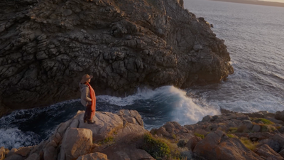 a man standing on top of a rock next to the ocean