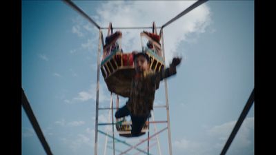 a man riding a roller coaster on top of a blue sky