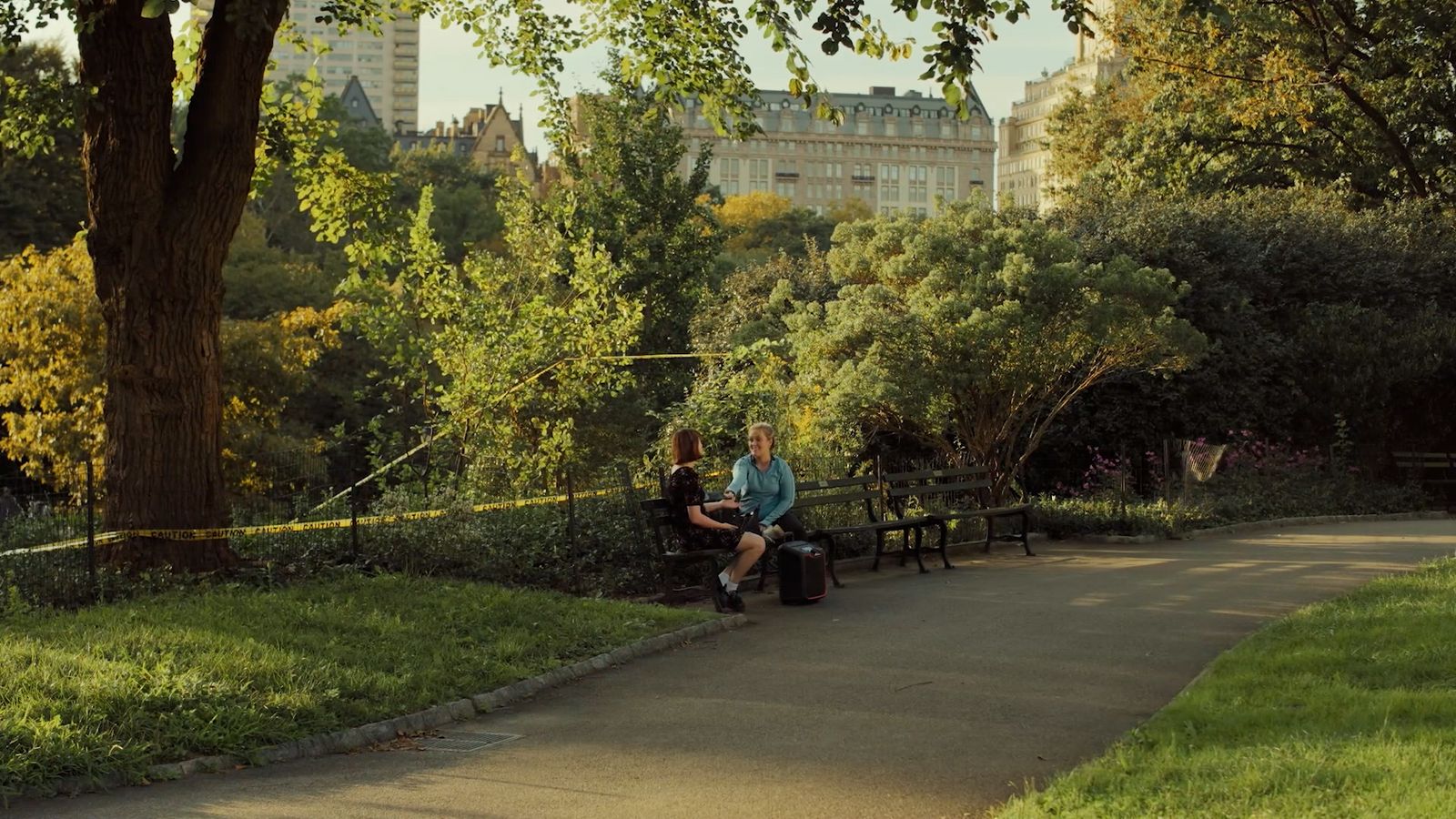 two people sitting on a bench in a park