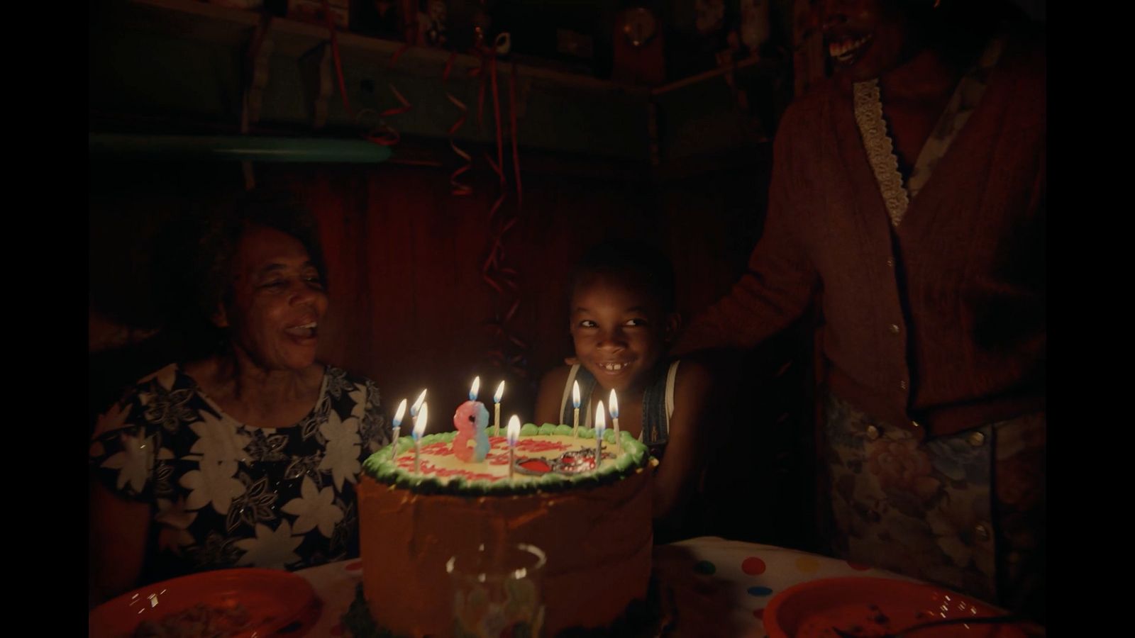 a group of people sitting around a cake with lit candles