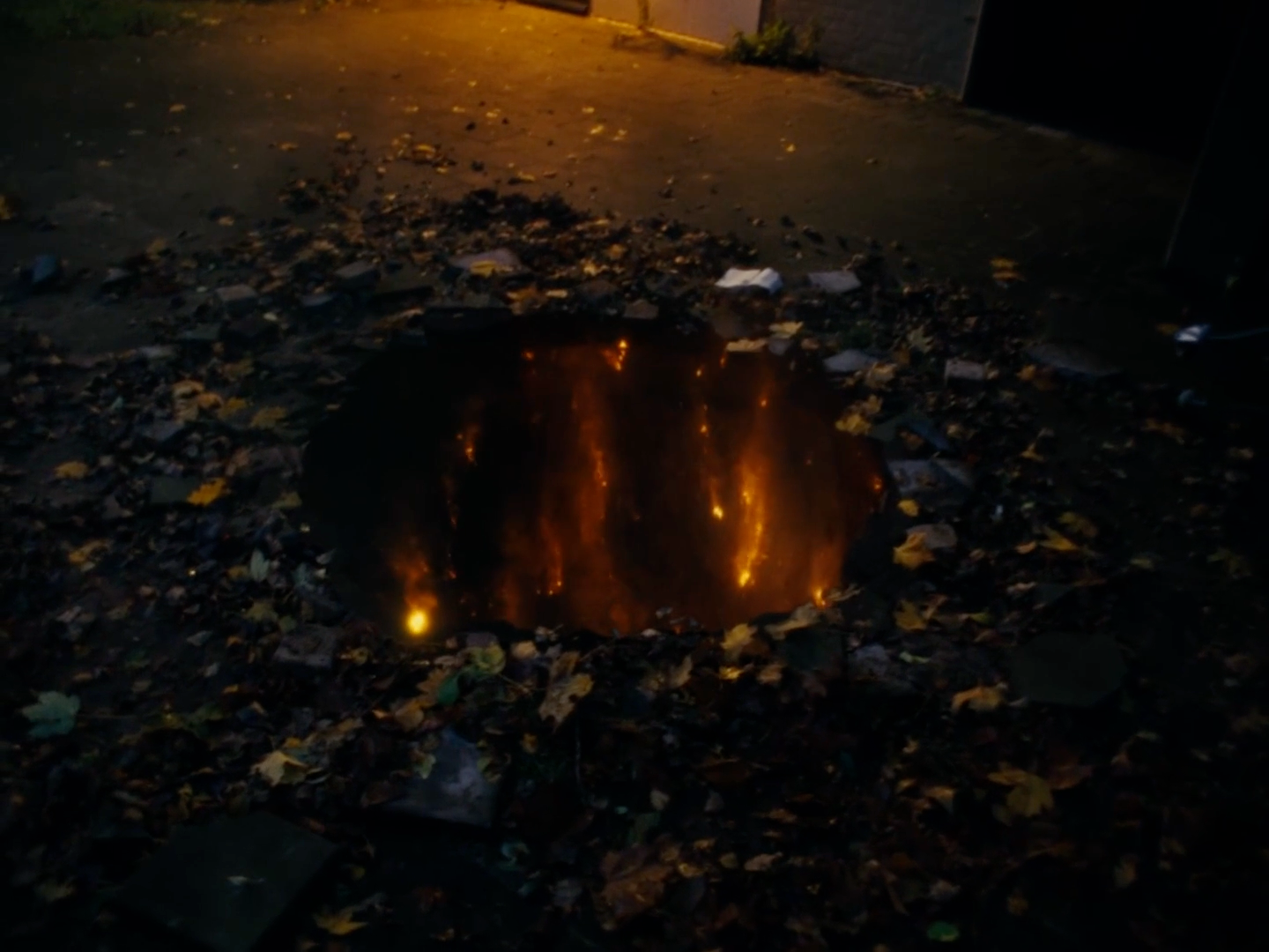 a hole in the ground with a street light in the background