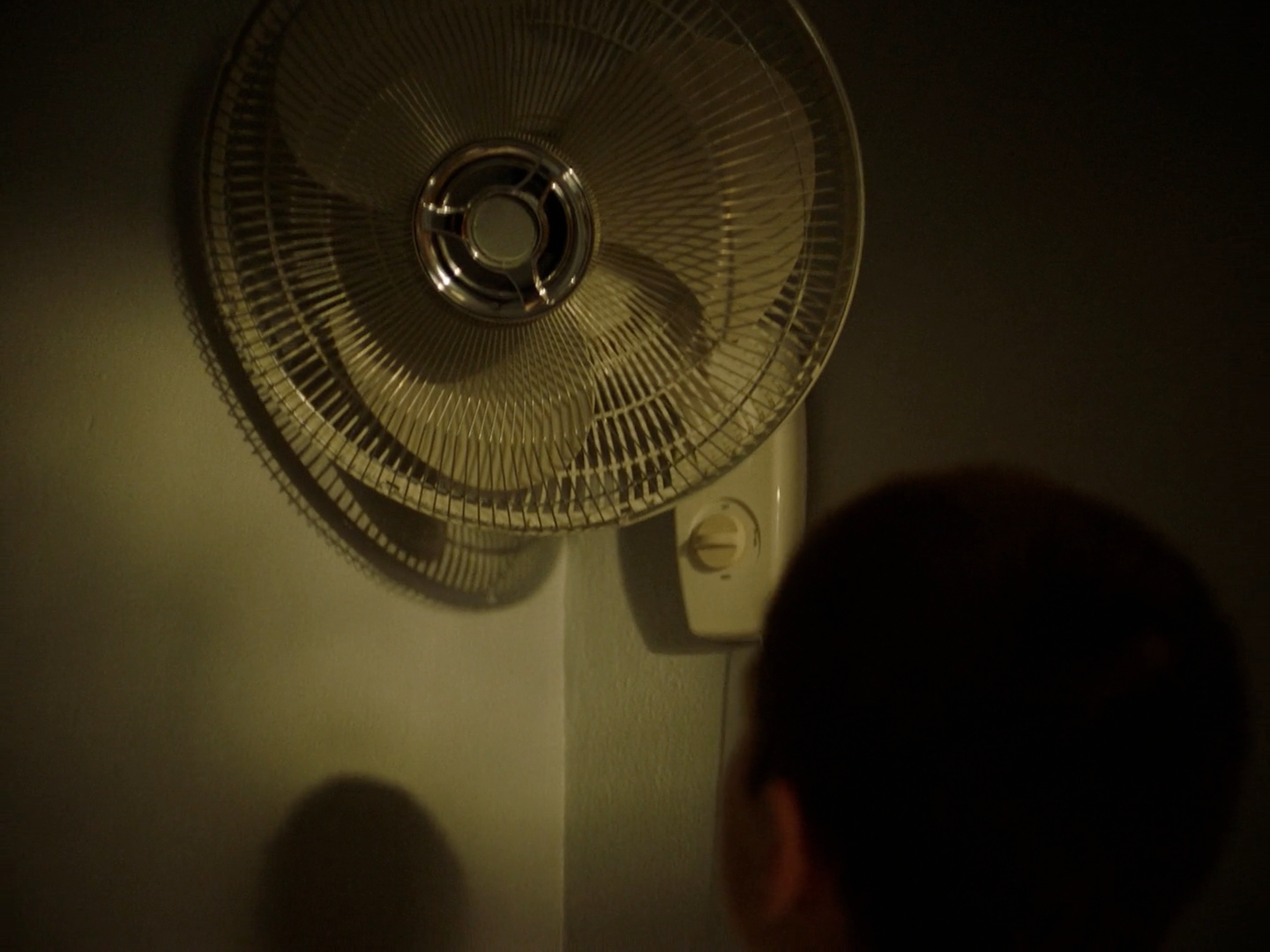 a person standing next to a wall mounted fan