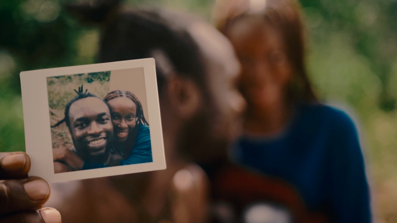 a person holding up a polaroid picture of two people