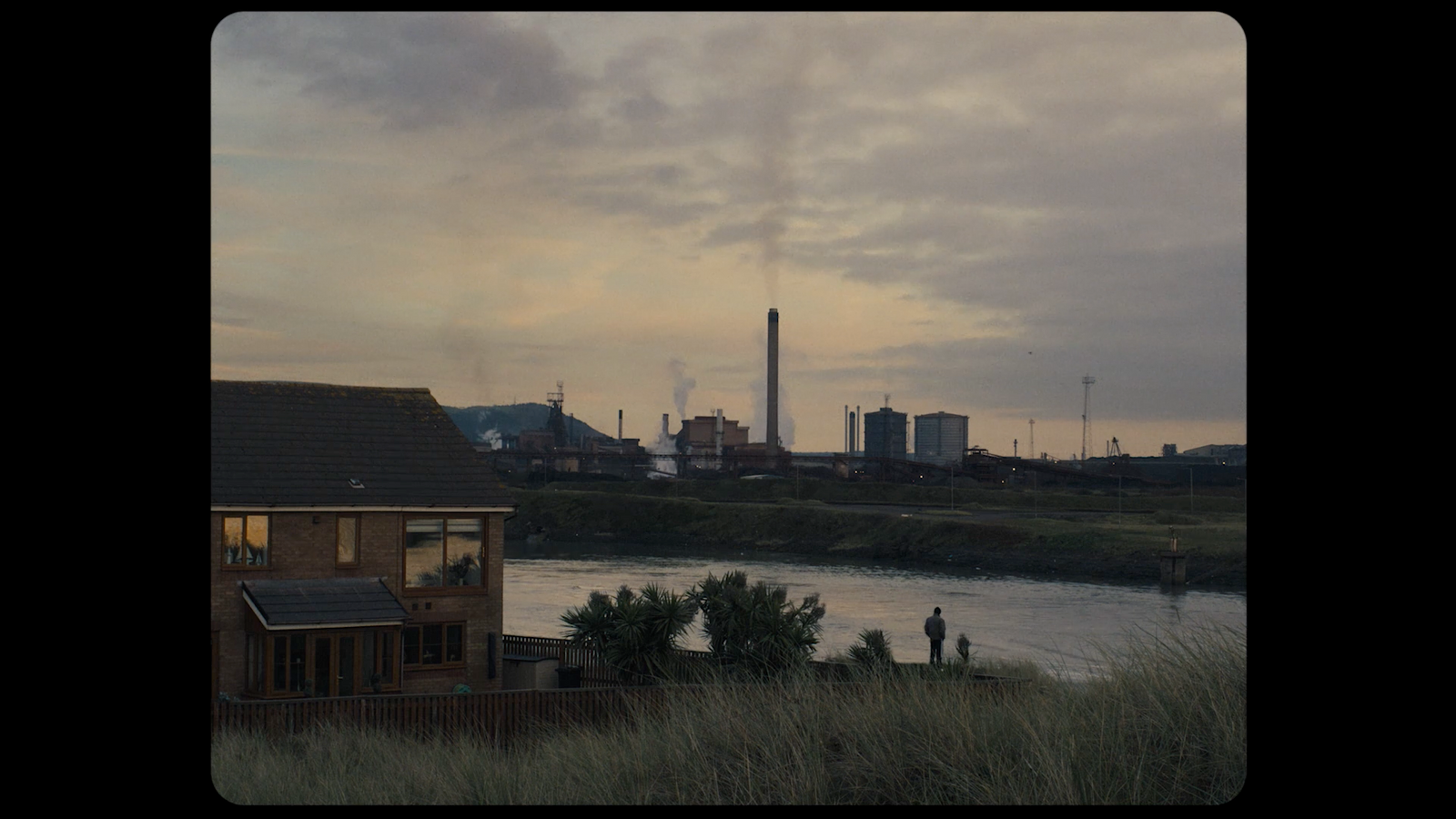 a view of a factory and a river at dusk