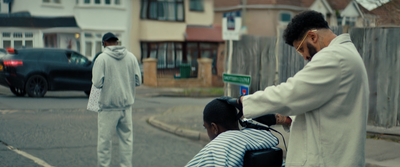 a man cutting another man's hair on the street