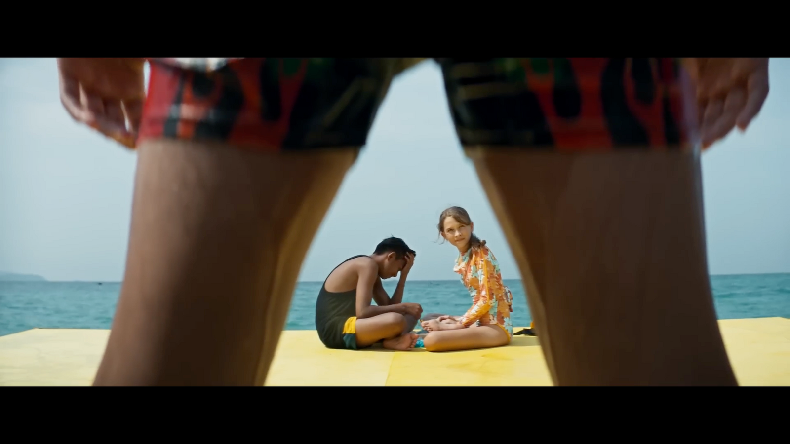 a couple of people sitting on top of a yellow surfboard