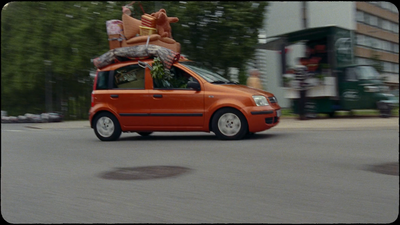 an orange van driving down a street next to tall buildings