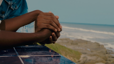 a couple of people holding hands near the ocean